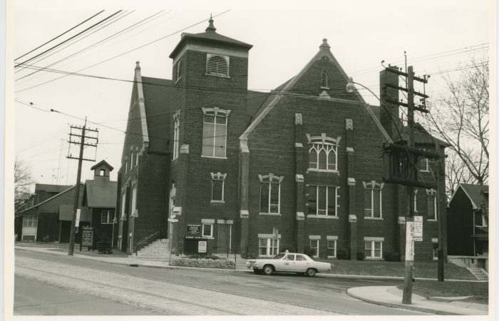 Sideview of a church on a corner in the middle of a city with a taxi parked outside