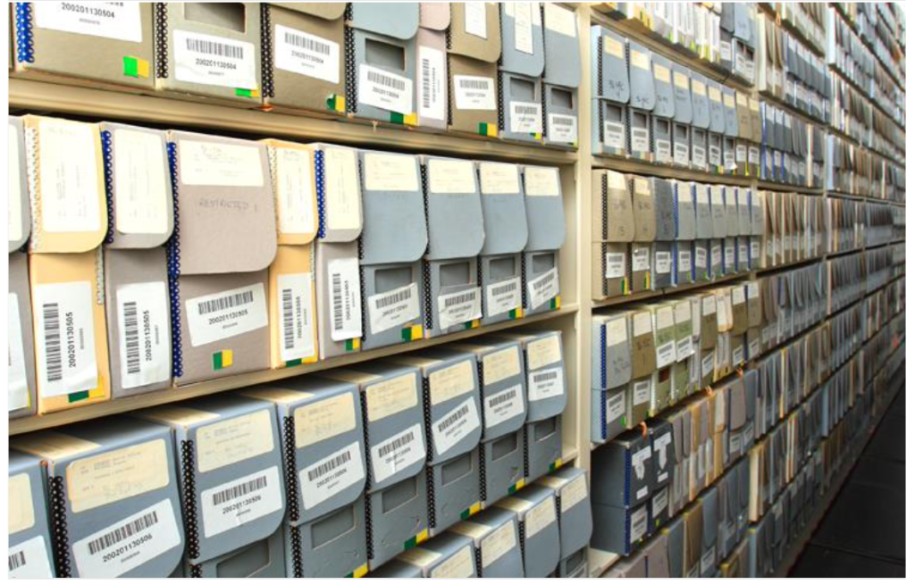 Archival boxes in rows on shelves with labels affixes to the front.